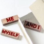 A wooden block with the words " me and i " written on it.