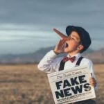 A young boy holding up a fake news sign.
