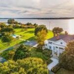 A large house with a lake in the background.