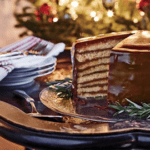 A cake is sitting on the table with plates and silverware.