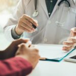A doctor is holding something in his hand while talking to someone.
