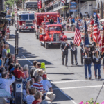 A parade with people and fire trucks on it.