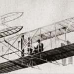 A black and white photo of two men in an airplane.