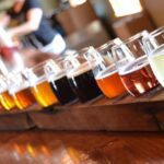 A row of different types of beer on a table.