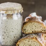 A jar of flour next to two pieces of bread.