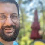 A man with glasses and beard smiling for the camera.