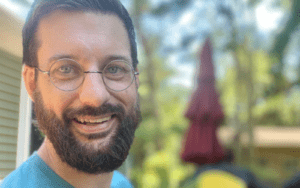 A man with glasses and beard smiling for the camera.