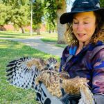 A woman holding an owl in her hands.
