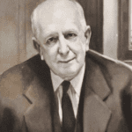 A man in suit and tie sitting down.