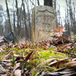 A grave in the woods with leaves on it