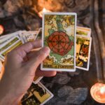 A person holding up a tarot card in front of candles.