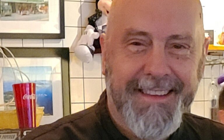 A man with a beard and mustache smiling for the camera.