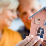 A couple holding up a small model of their home.