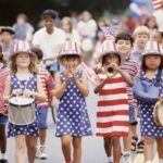 A group of children in patriotic outfits marching down the street.