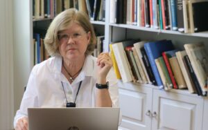 A woman sitting at her laptop in front of some books.