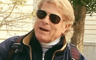 A man with sunglasses on and wearing a jacket.