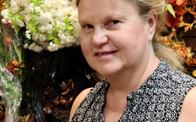 A woman standing in front of flowers and plants.