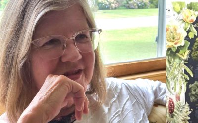 A woman with glasses sitting in front of a window.