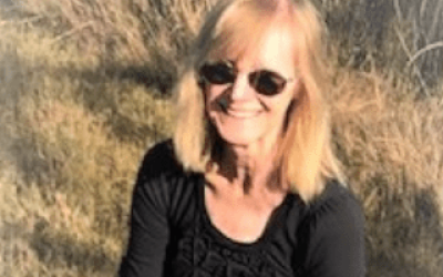 A woman wearing sunglasses and smiling for the camera.