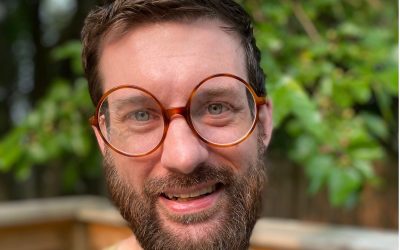 A man with beard and glasses smiling for the camera.
