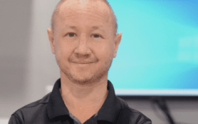 A man with bald head and mustache wearing black shirt.