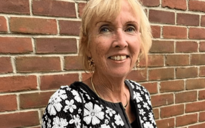 A woman standing in front of a brick wall.