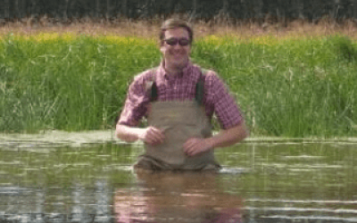 A man in waders sitting on the water.