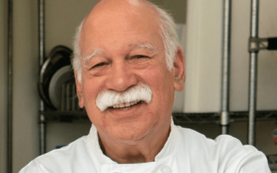 A man with white hair and mustache smiling.
