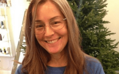 A woman with long hair and glasses smiling.